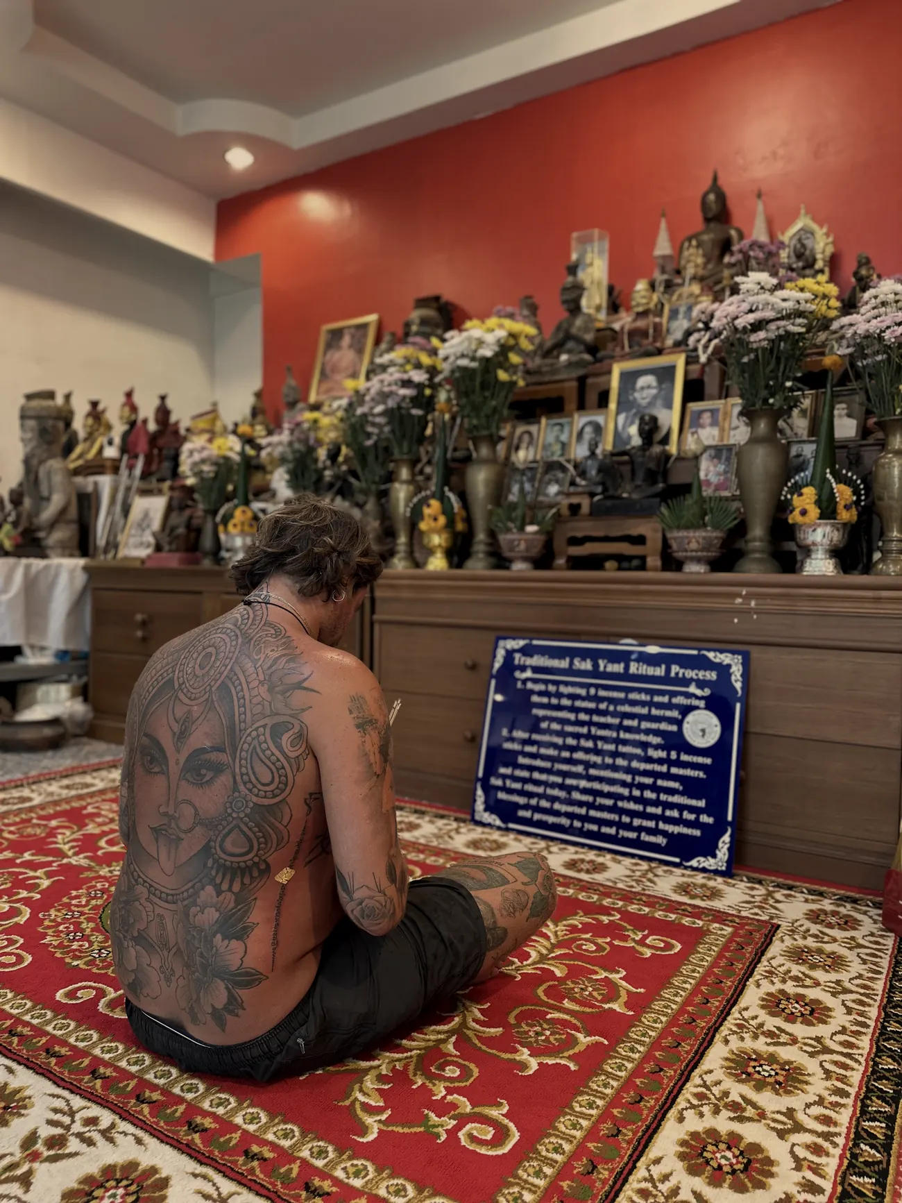 A client with a full back Sak Yant sitting before the shrine