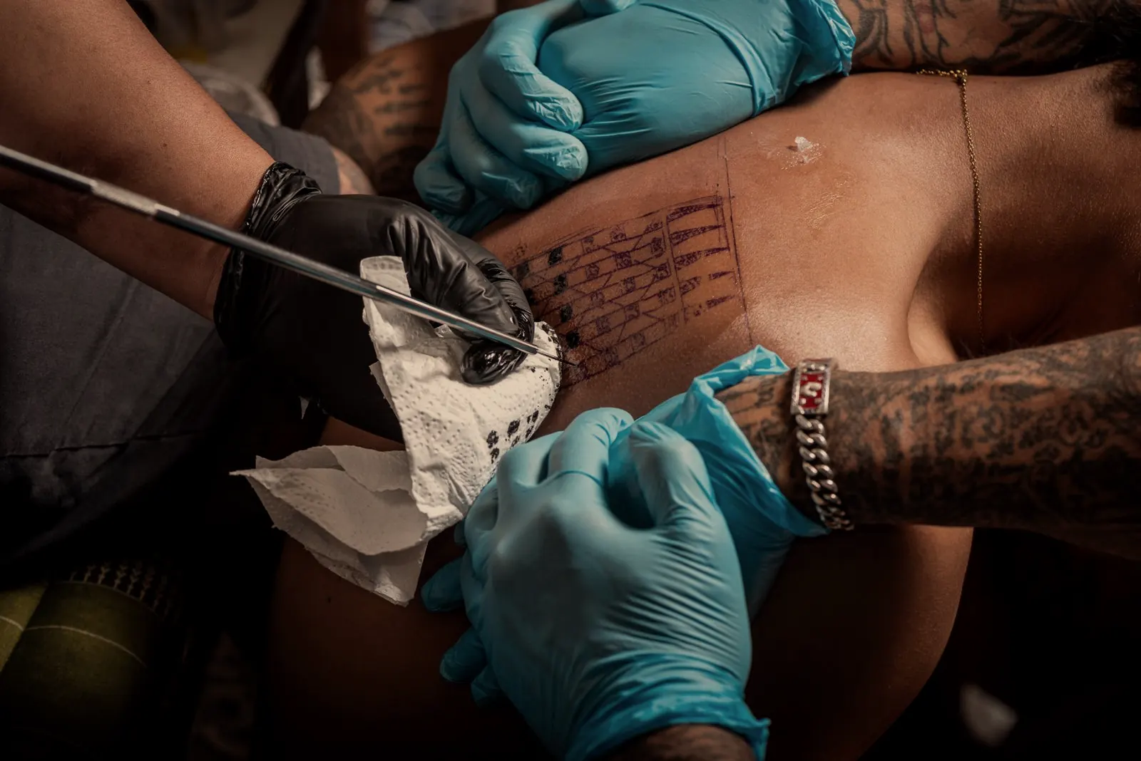 A Sak Yant being hand-poked with gloves and a traditional needle