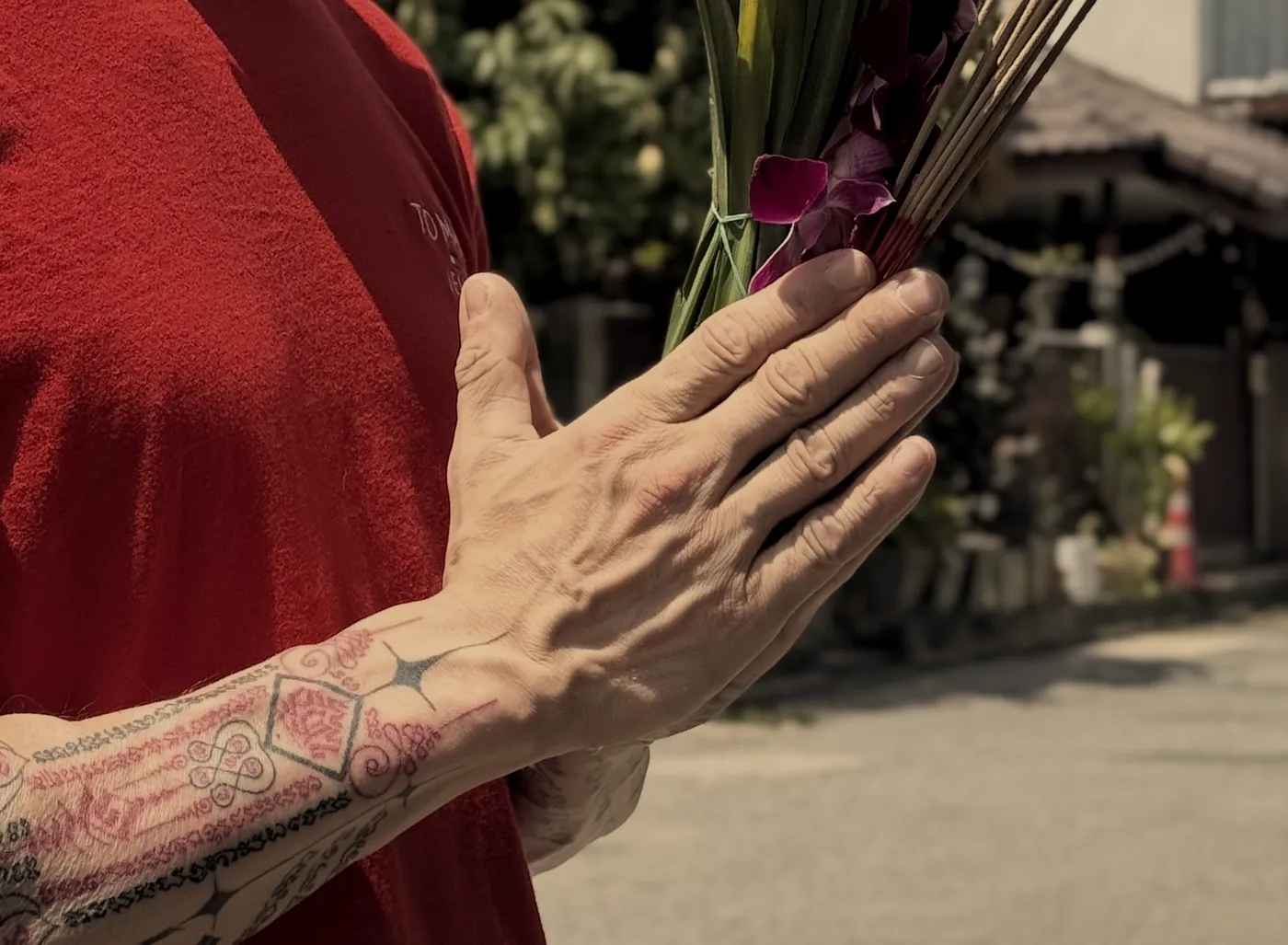 Tattooed hands held together in a wai